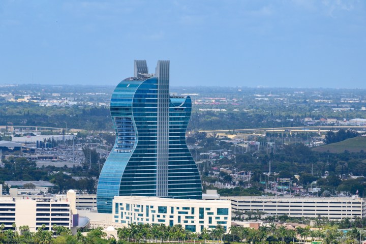 A guitar-shaped skyscraper in a cityscape with a clear sky.