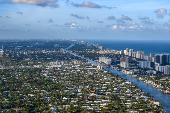 Aerial view of a coastal city with canals and high-rise buildings along the shoreline.