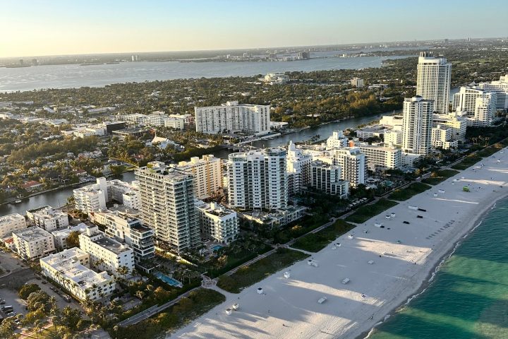 Aerial view of a beachside cityscape with white sand and turquoise water.