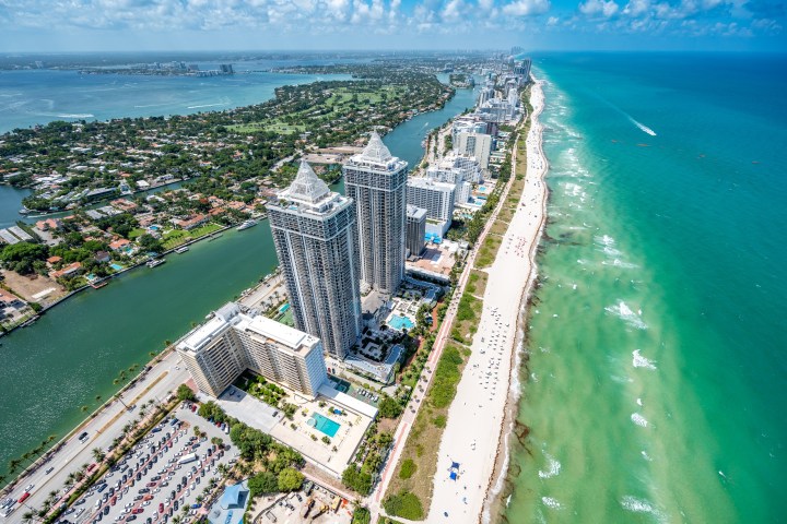 Aerial view of a coastal city with skyscrapers, beach, and ocean.
