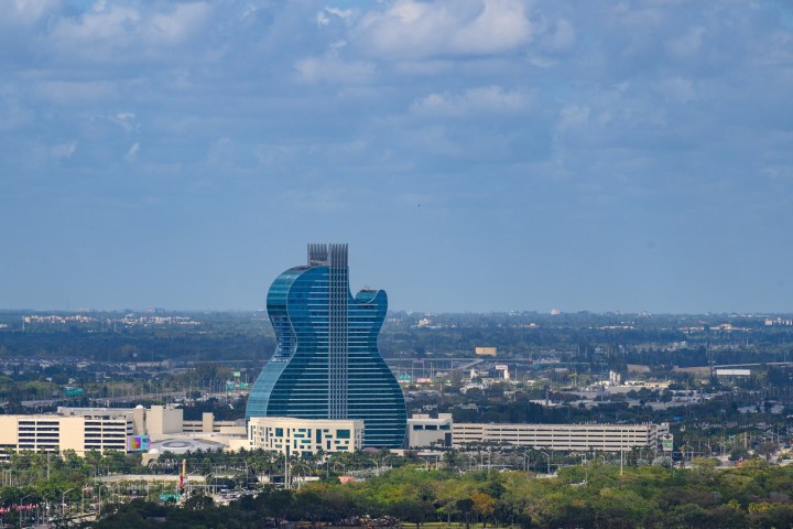Guitar-shaped building rising above the cityscape under a partly cloudy sky.