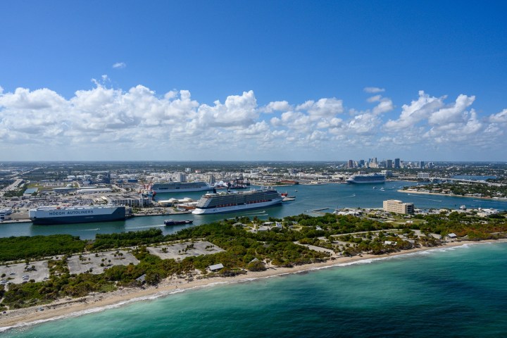 Aerial view of cruise ships docked in a port city with clear skies.