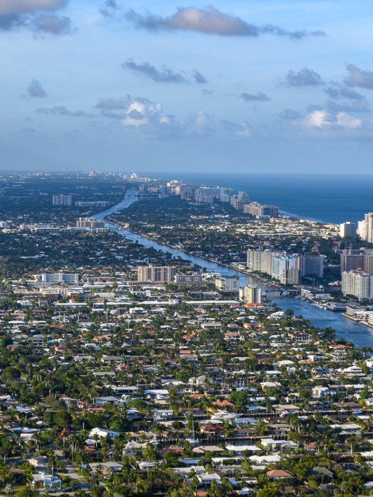 Aerial view of a coastal cityscape with high-rise buildings and waterways.