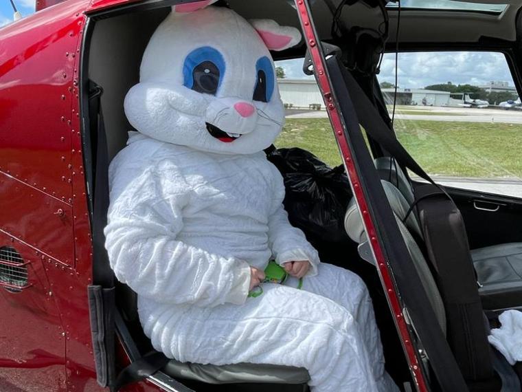 Person in bunny costume sitting inside a red helicopter.