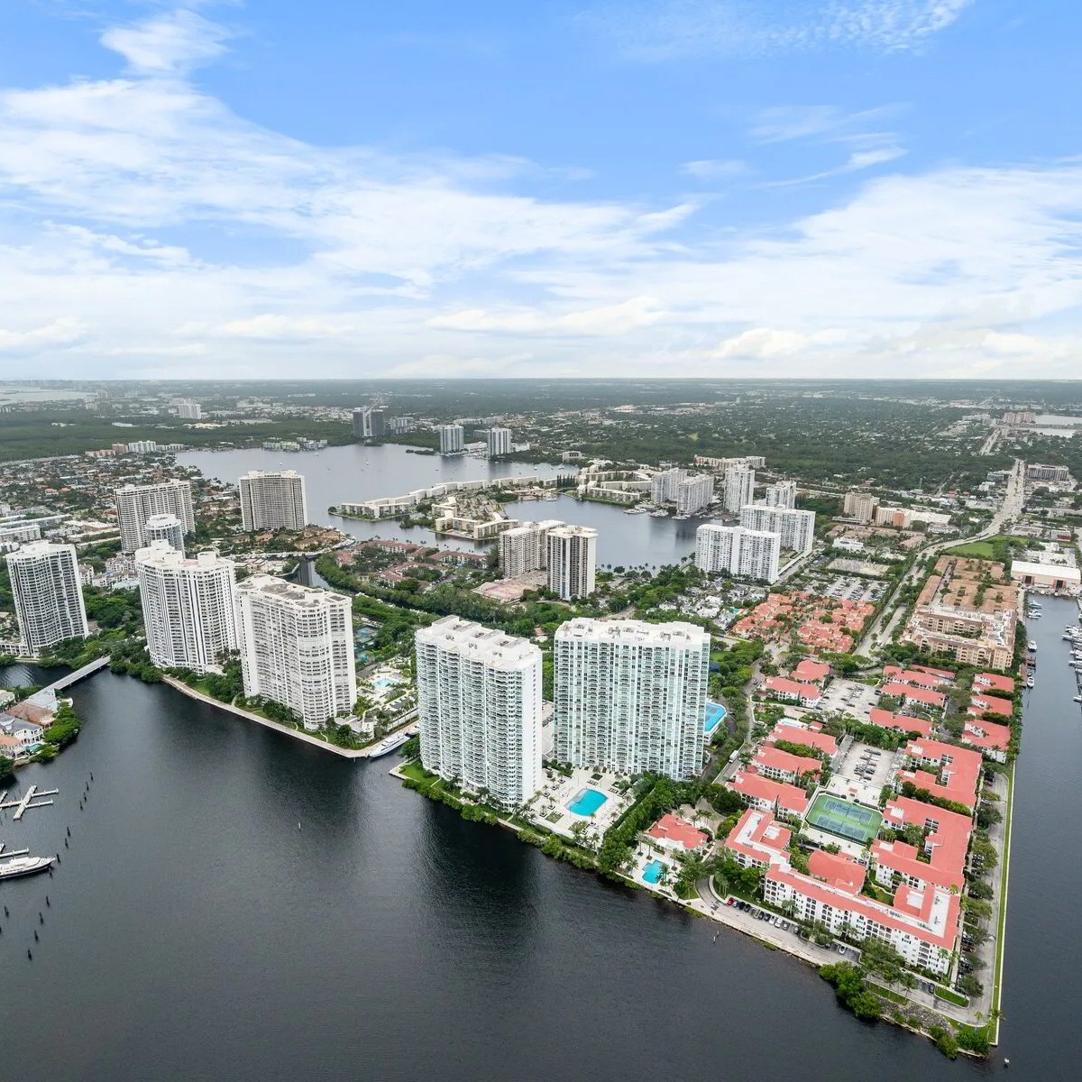 Aerial view of a city near water with tall buildings and clouds in the sky.