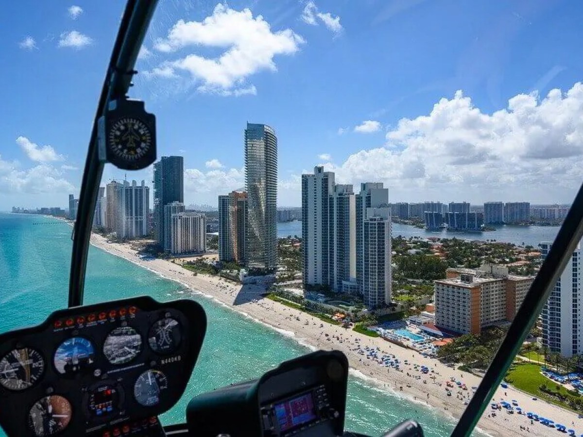 View from a helicopter over Miami beach with skyscrapers and ocean.