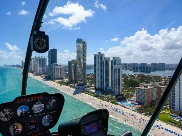 View from a helicopter over Miami beach with skyscrapers and ocean.