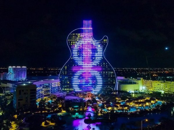 Guitar-shaped building lit up at night with purple and blue lights.