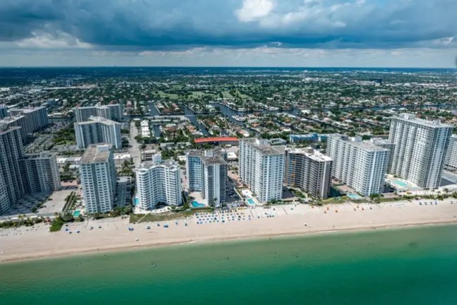 Aerial view of a beach with high-rise buildings and blue sky.